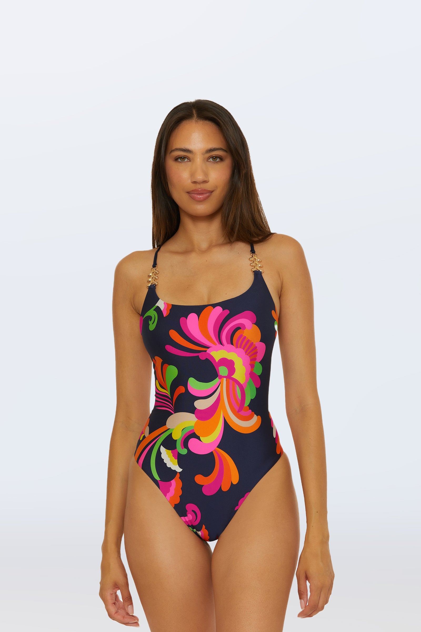 A woman stands facing forward against a plain light background, wearing the Twist Back One-Piece Swimsuit - Palms Paradise in a multi-color abstract floral pattern.
