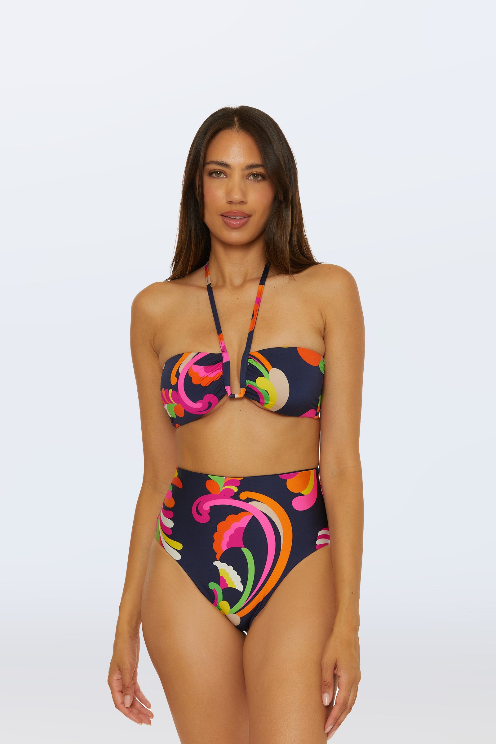 A woman wearing the Bandeau Swim Top - Palms Paradise, featuring a high-waisted bikini with a colorful neon swirl pattern, stands against a plain light background.