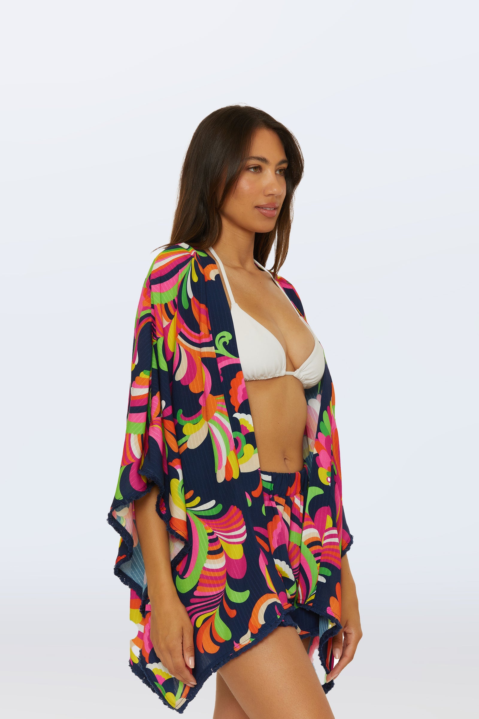 A woman models the Kimono Swim Cover-Up - Palms Paradise over a white bikini top and coordinating shorts, standing against a plain light background.