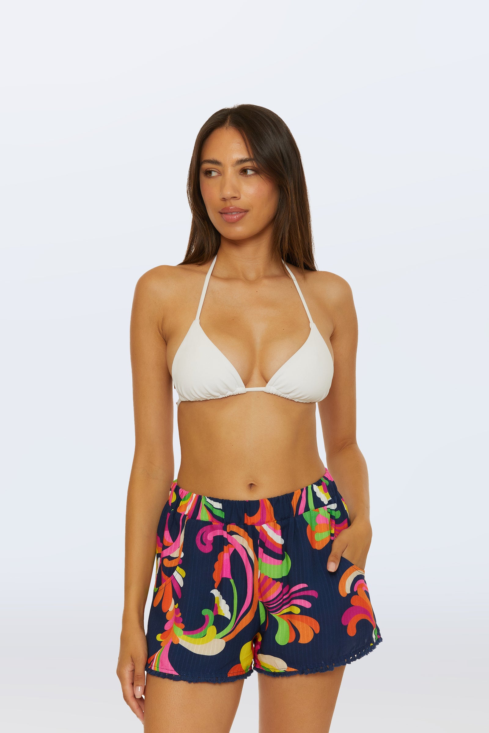A woman wears the Cover-Up Short - Palms Paradise in Multi with a white bikini top, standing with one hand in her pocket against a light background.