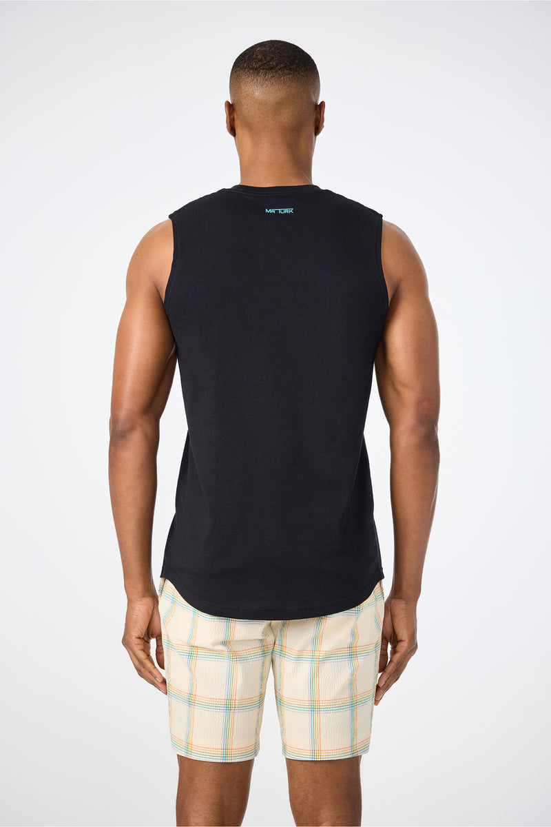A man, with his back to the camera, wears the Sleeveless Muscle Tee - Pride and light plaid shorts against a plain white background.