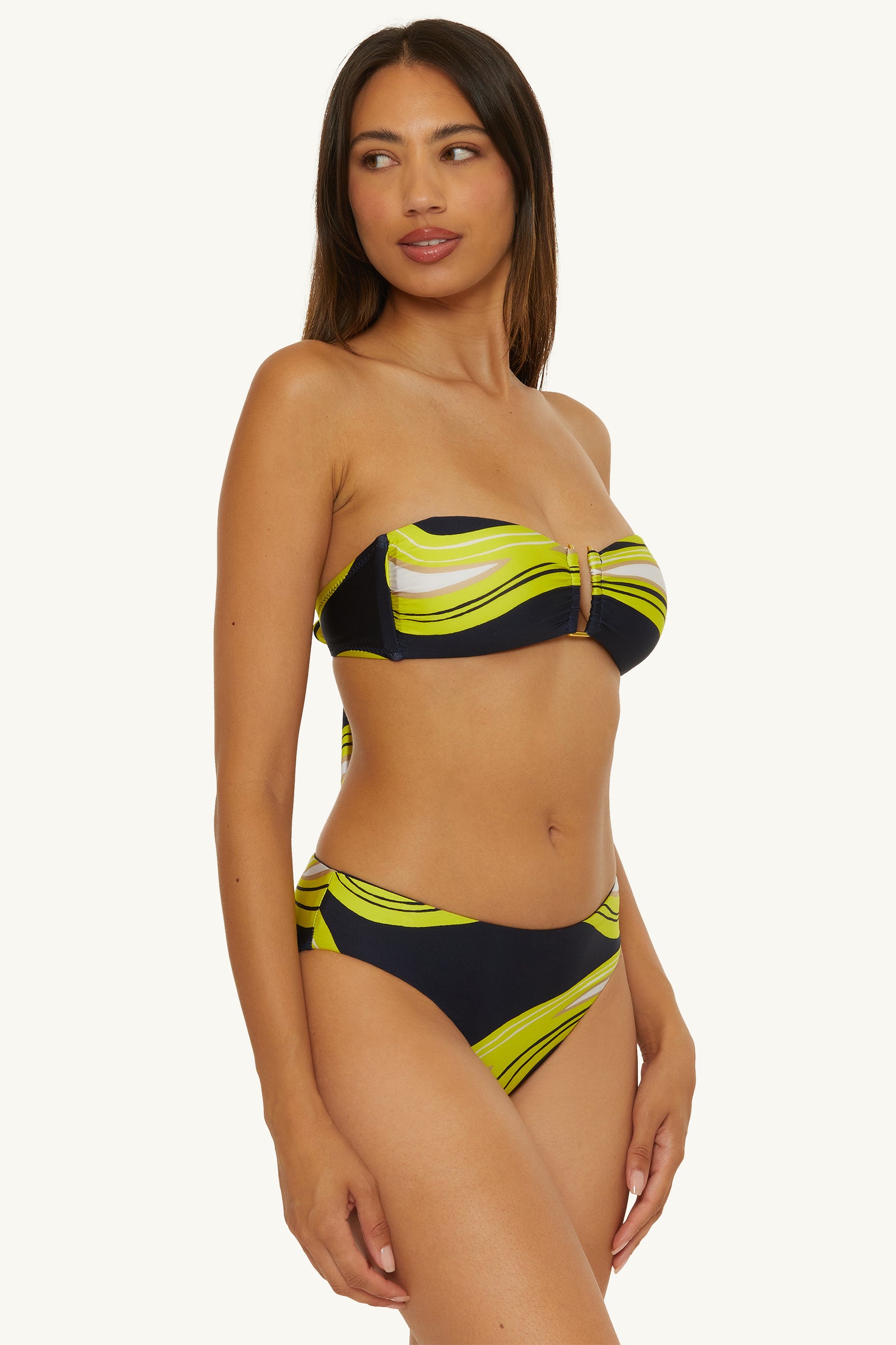 A woman models the Strapless Bandeau Swim Top - Serena Swirl, featuring a yellow and green swirl pattern on black, standing against a plain light background.