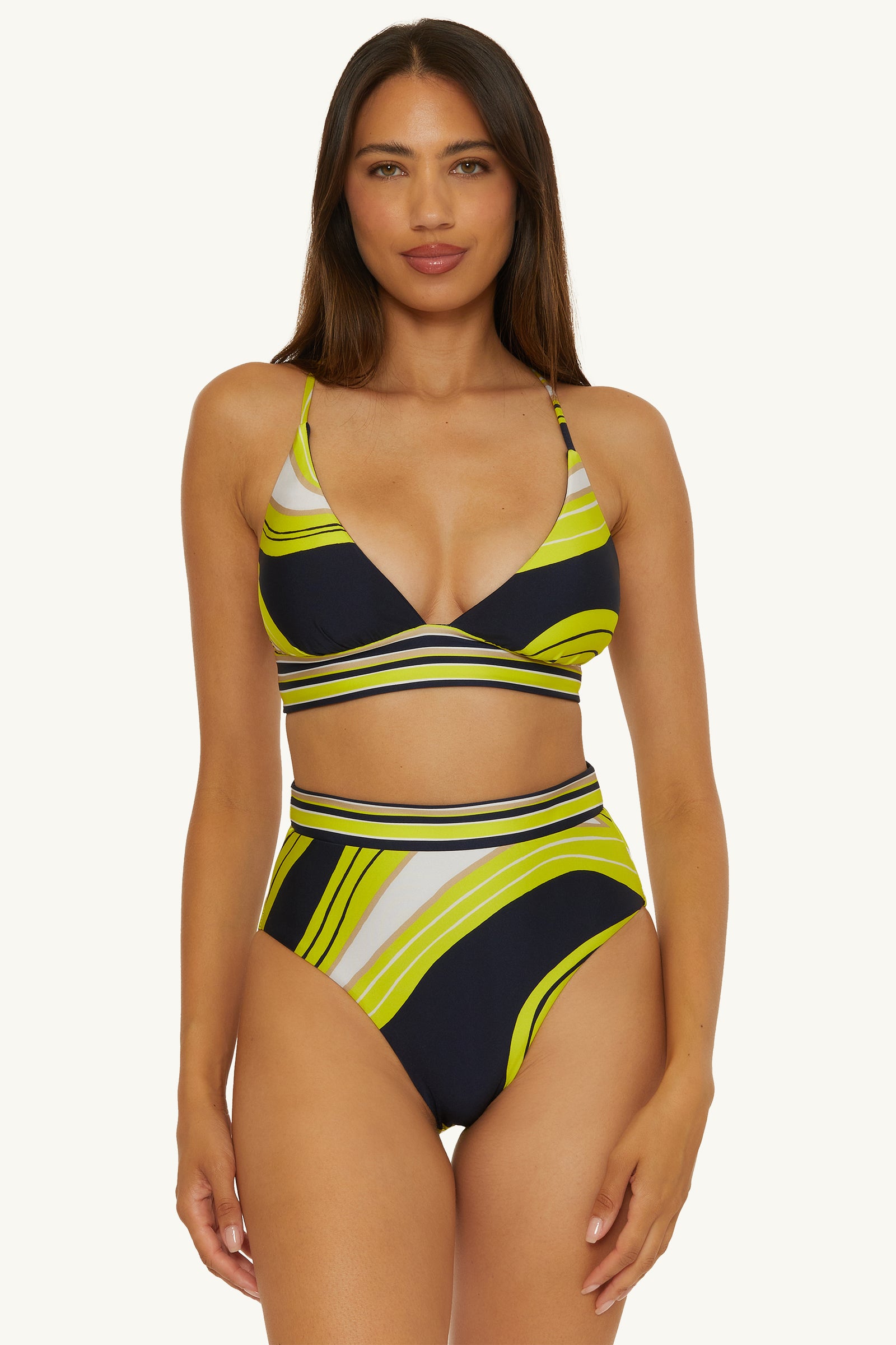 Woman models the Reversible High-Waist Swim Bottom - Serena Swirl, featuring a geometric print in yellow, green, navy, and white against a plain light background.