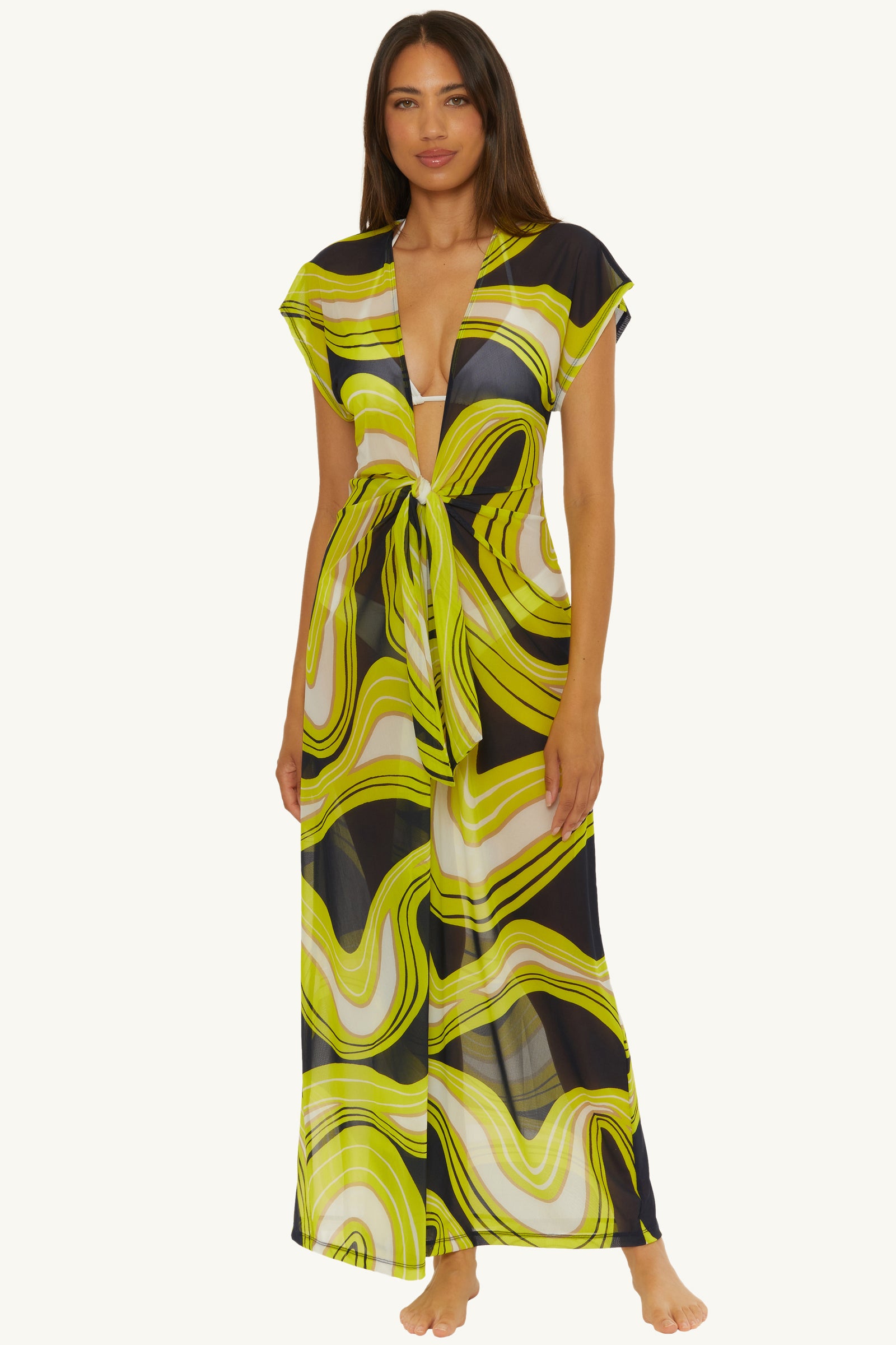 A woman stands barefoot in the Mesh Tie-Front Maxi Dress Cover-Up – Serena Swirl, featuring a deep V-neck, front tie, and bold wavy pattern in yellow, green, black, and white (Serena Swirl Swim).