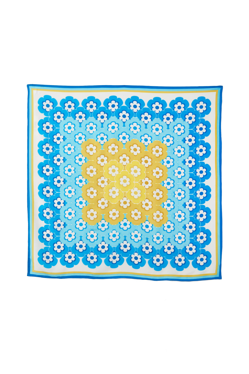 The Flower Power Scarf is a square accessory in MULTI, showcasing retro floral patterns with a yellow center, concentric rows of blue, yellow, and white flowers, all framed by shades of blue and a blue border.