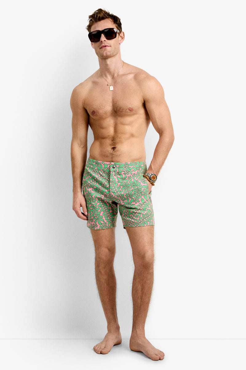 A shirtless man wearing the Honolulu Board Short - Vines, sunglasses, a necklace, and a bracelet stands barefoot against a plain white background.