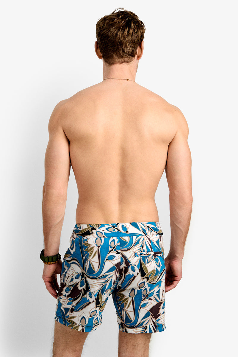 A shirtless man is seen from behind wearing the Honolulu Board Short, featuring blue with tan, beige, and white abstract patterns, against a plain white background.