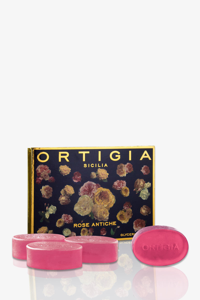Three pink oval soaps from the Ortigia Soap 4P Set are arranged in front of a decorative Ortigia Sicilia Rosé Antiche box, featuring a floral design, gold trim, and the prominent Ortigia brand name.