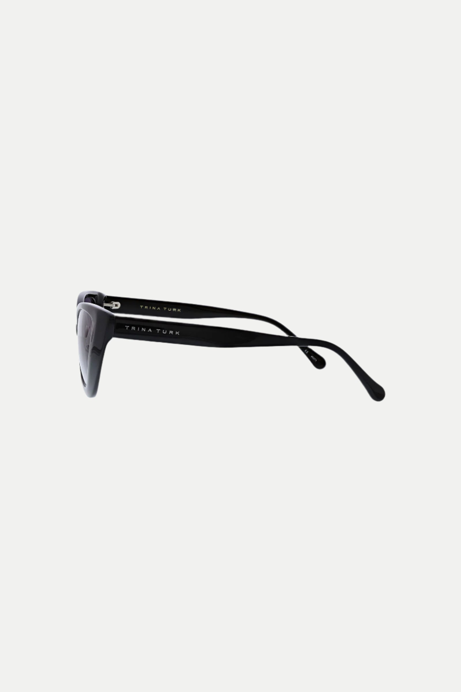 Side view of Tenerife Cat Eye Acetate Sunglasses with thick black arms and Trina Turk printed in white on the temple, set against a plain white background.