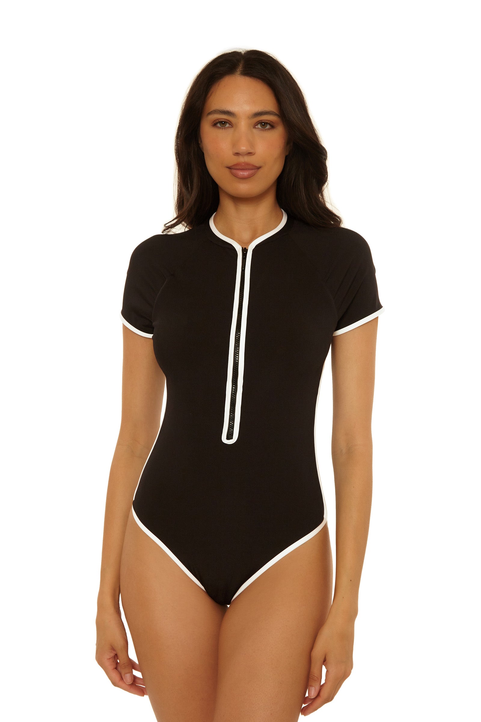 A woman wearing the Triumph Short-Sleeve Zip-Up Paddlesuit, featuring black fabric with white trim and a front zipper, stands against a plain white background.