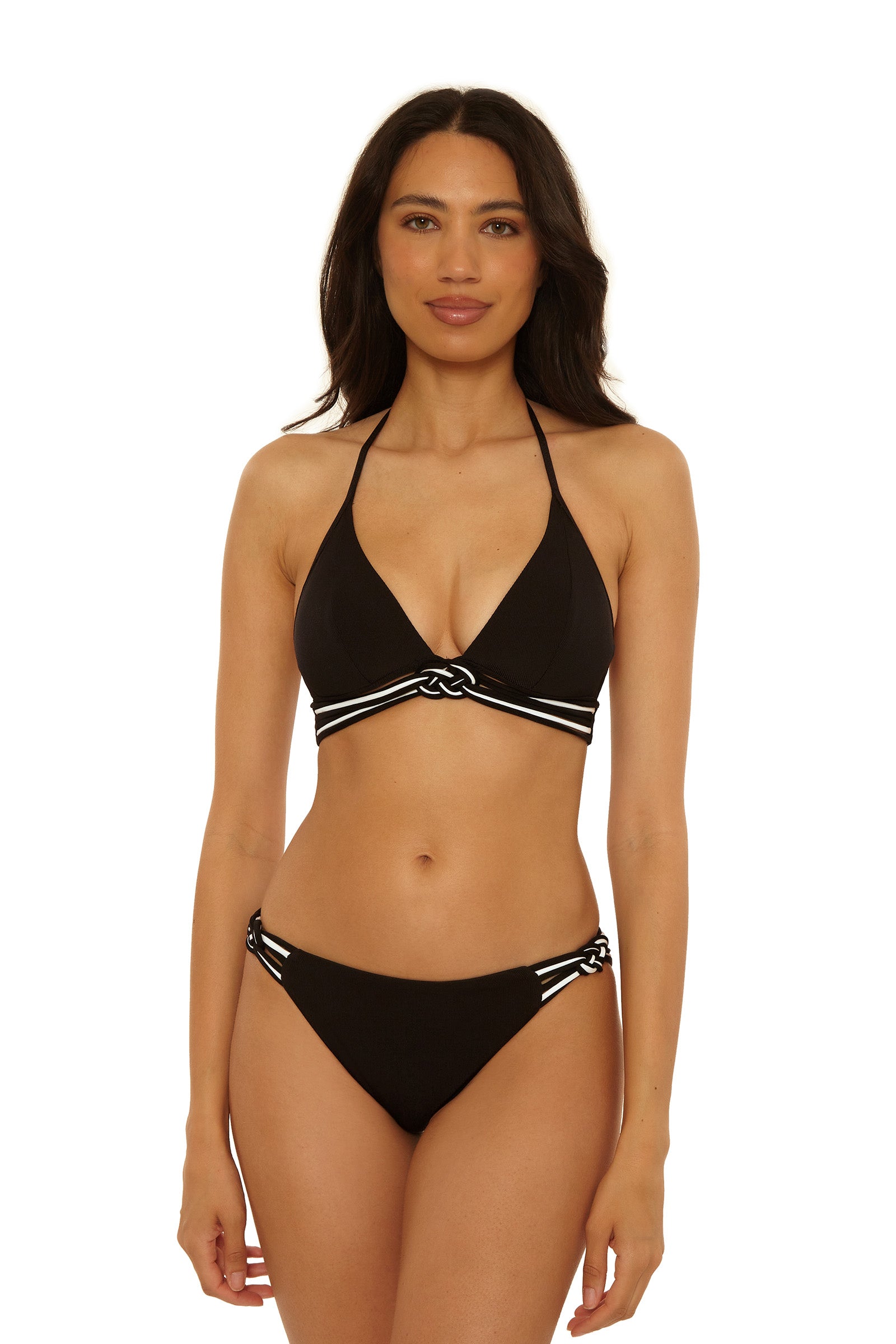 A woman with long dark hair and a neutral expression wears the Triumph Braided Hipster Swim Bottom, a black bikini featuring white striped trim and knot details on the top and sides of the bottoms.