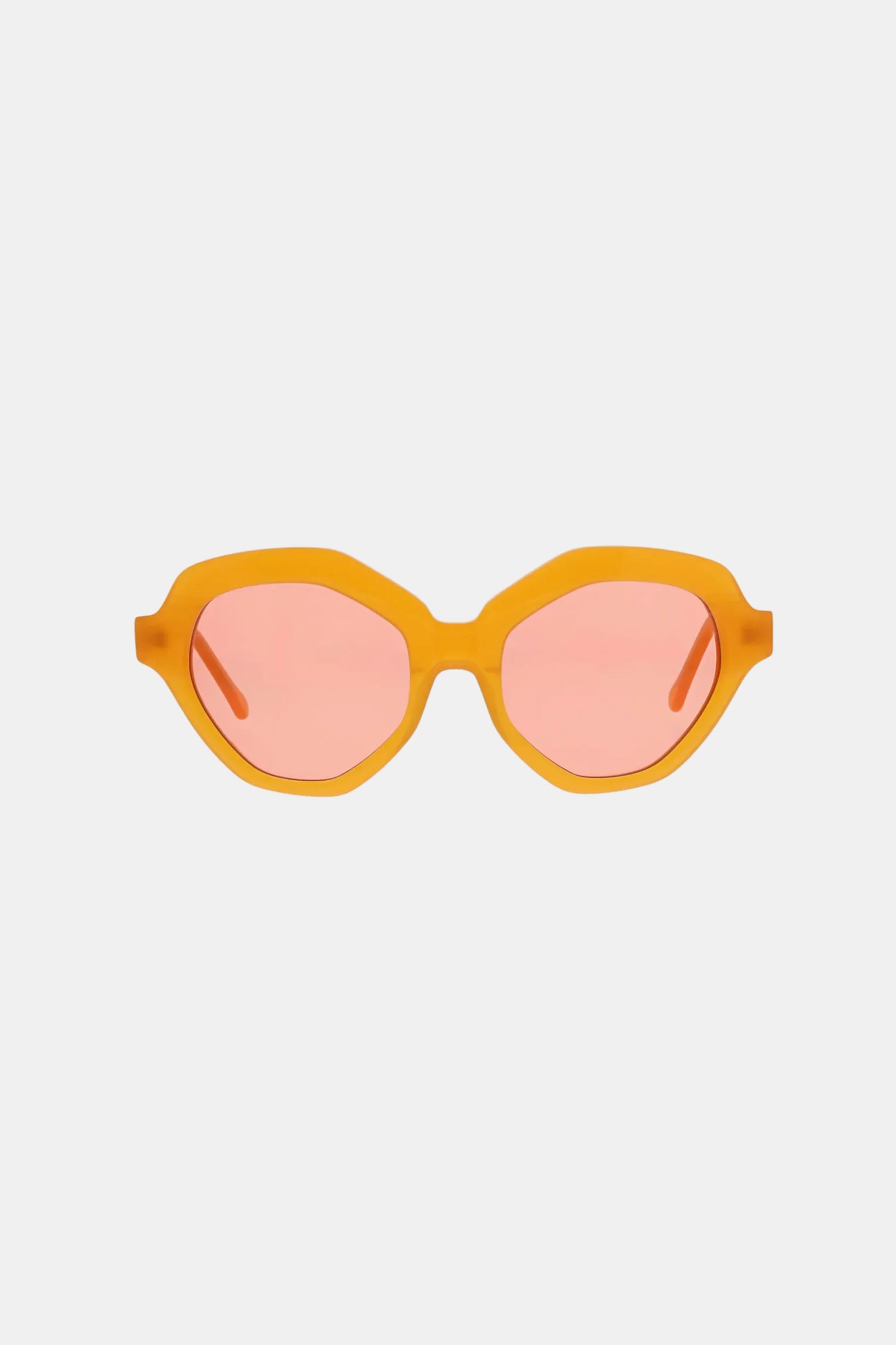 The Ipanema Sunglasses feature a bright orange chunky geometric frame with pink-tinted oval lenses, shown against a plain white background.