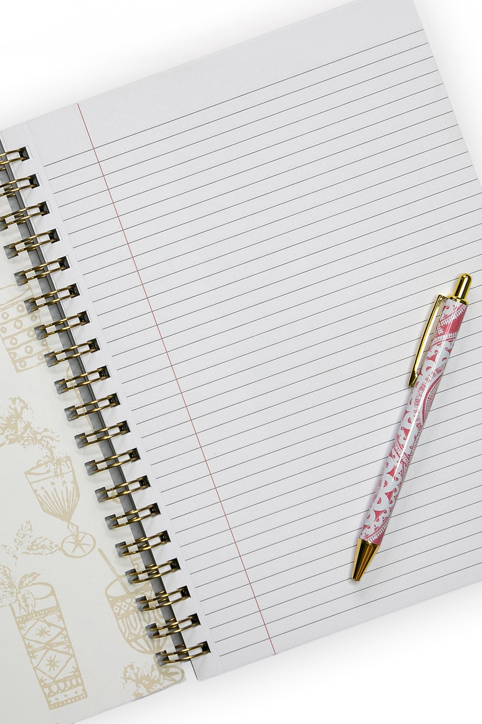 An open Tt Happy Hour Gold Notebook with college-ruled paper rests on a white surface. A pink and white patterned pen with gold accents sits on the right page, while the left shows part of its decorative cover with light gold illustrations.