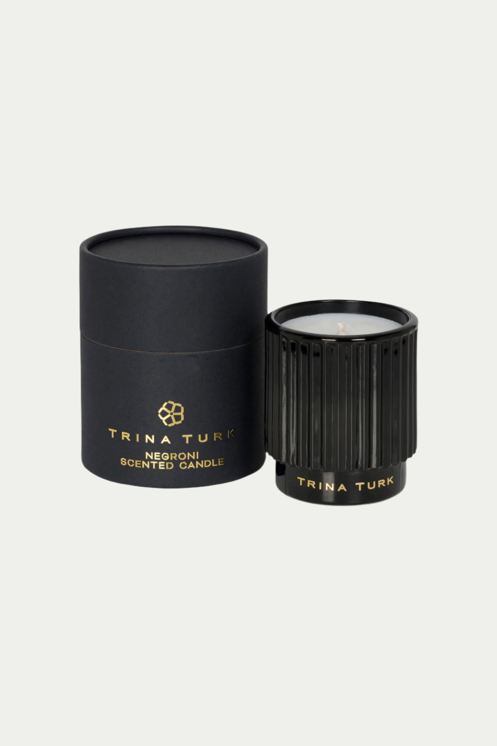 A black TT x Perch Negroni Candle sits beside its matching black and gold round box, both featuring gold lettering on a light background.