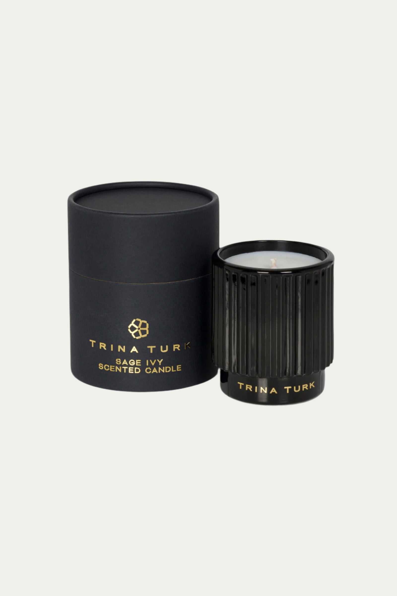 A black TT x Perch Sage Ivy Candle in a ribbed glass holder sits beside its matching cylindrical box, both labeled with the product name in gold on a light gray background.