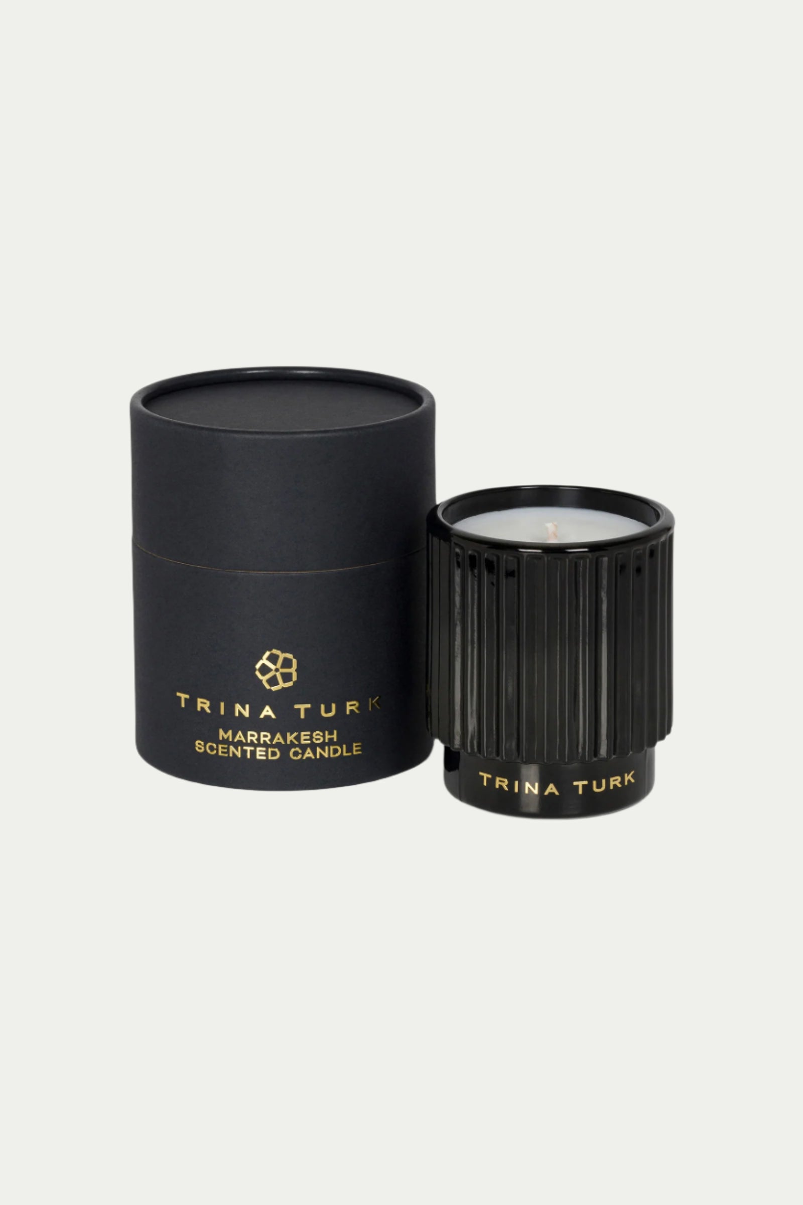 A black TT x Perch Marrakesh Candle sits beside its matching black cylindrical box, both labeled with Trina Turk branding, on a light background.