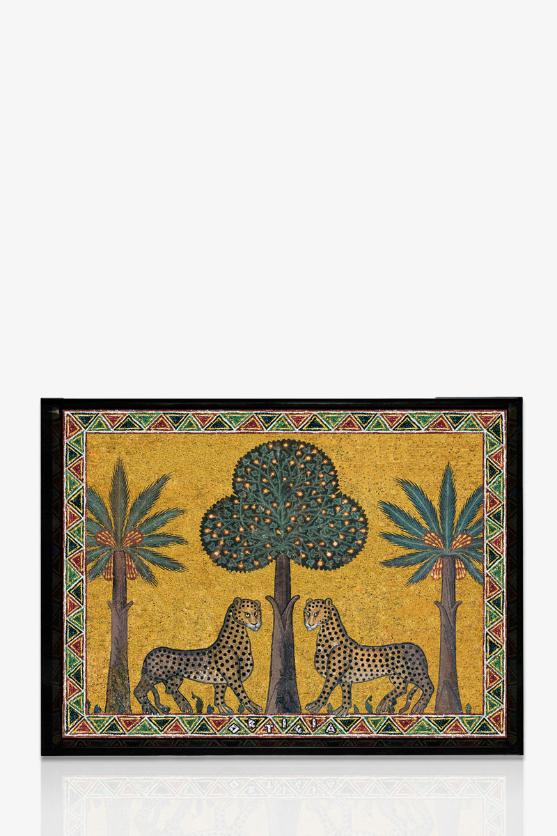 The Ortigia Small Tray features two leopards facing each other beneath a central tree, with palm trees on each side. It has a golden yellow background and a geometric border in red, green, black, and white.
