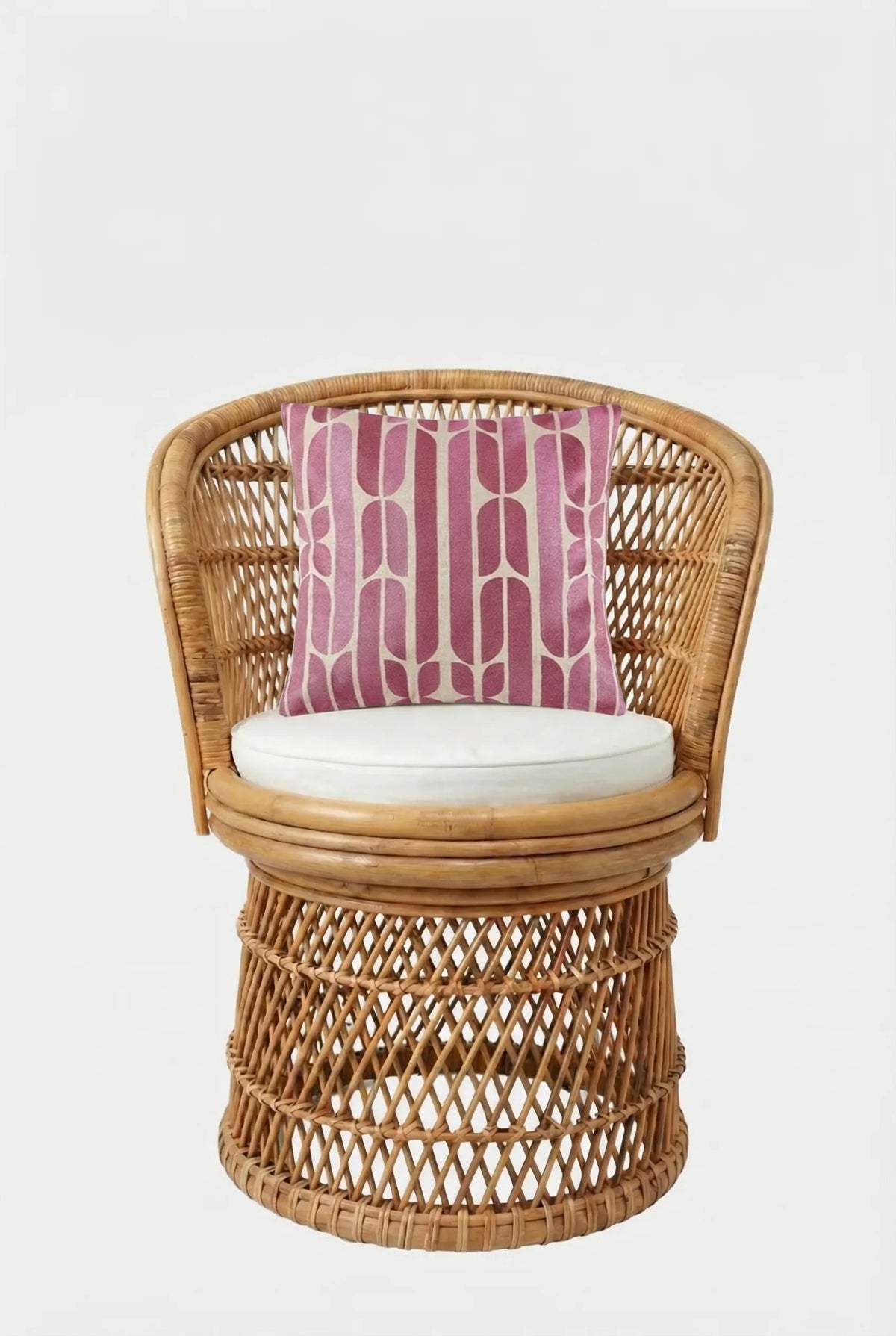 A rattan chair with a round white cushion and the Palmdale Emb Pillow 20X20", which has a pink and white geometric pattern, set against a plain white background.