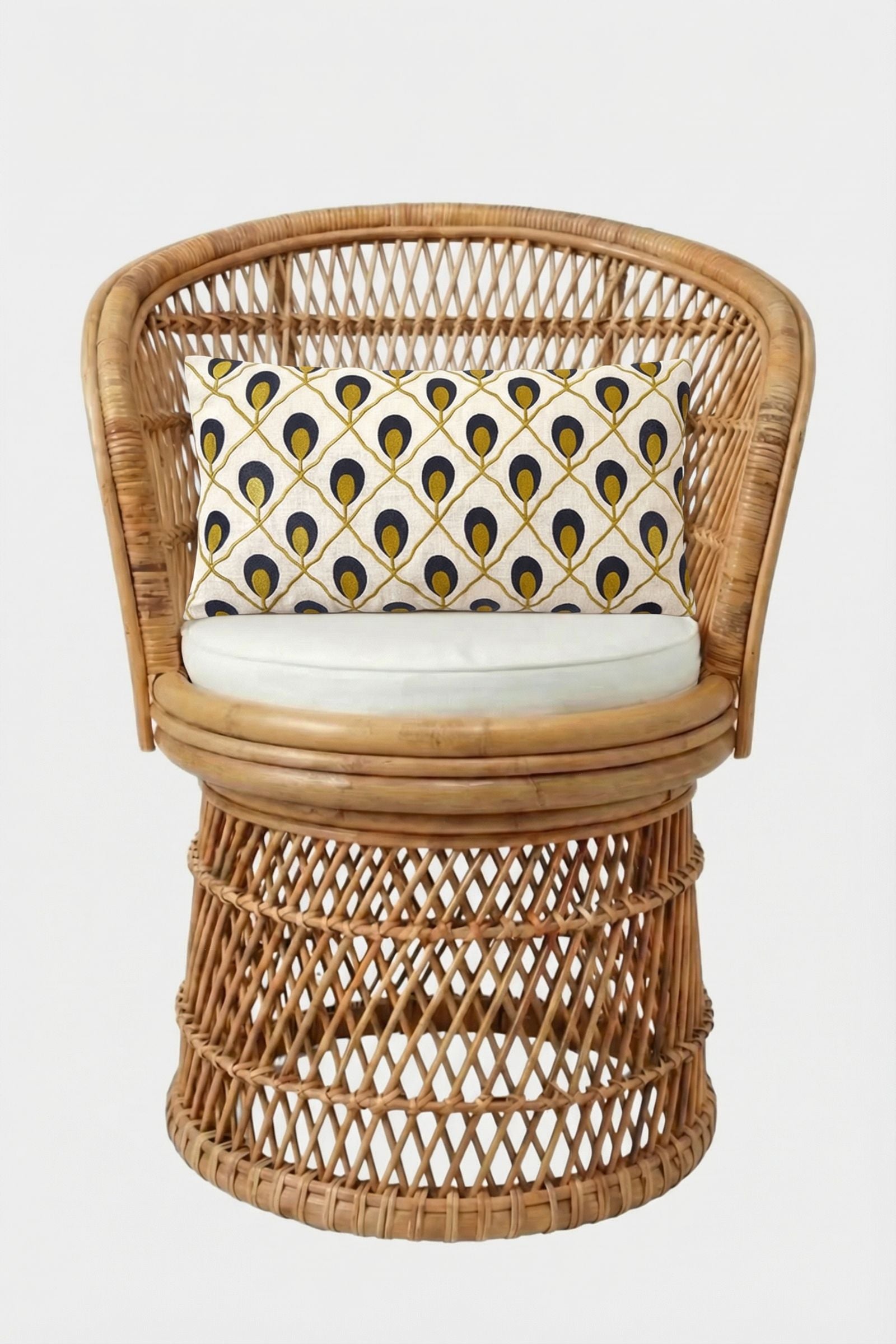 A round rattan chair with a white seat cushion and the Roseville Embroidered Lumbar Pillow, showcasing a yellow, black, and gray geometric pattern, set against a plain white background.