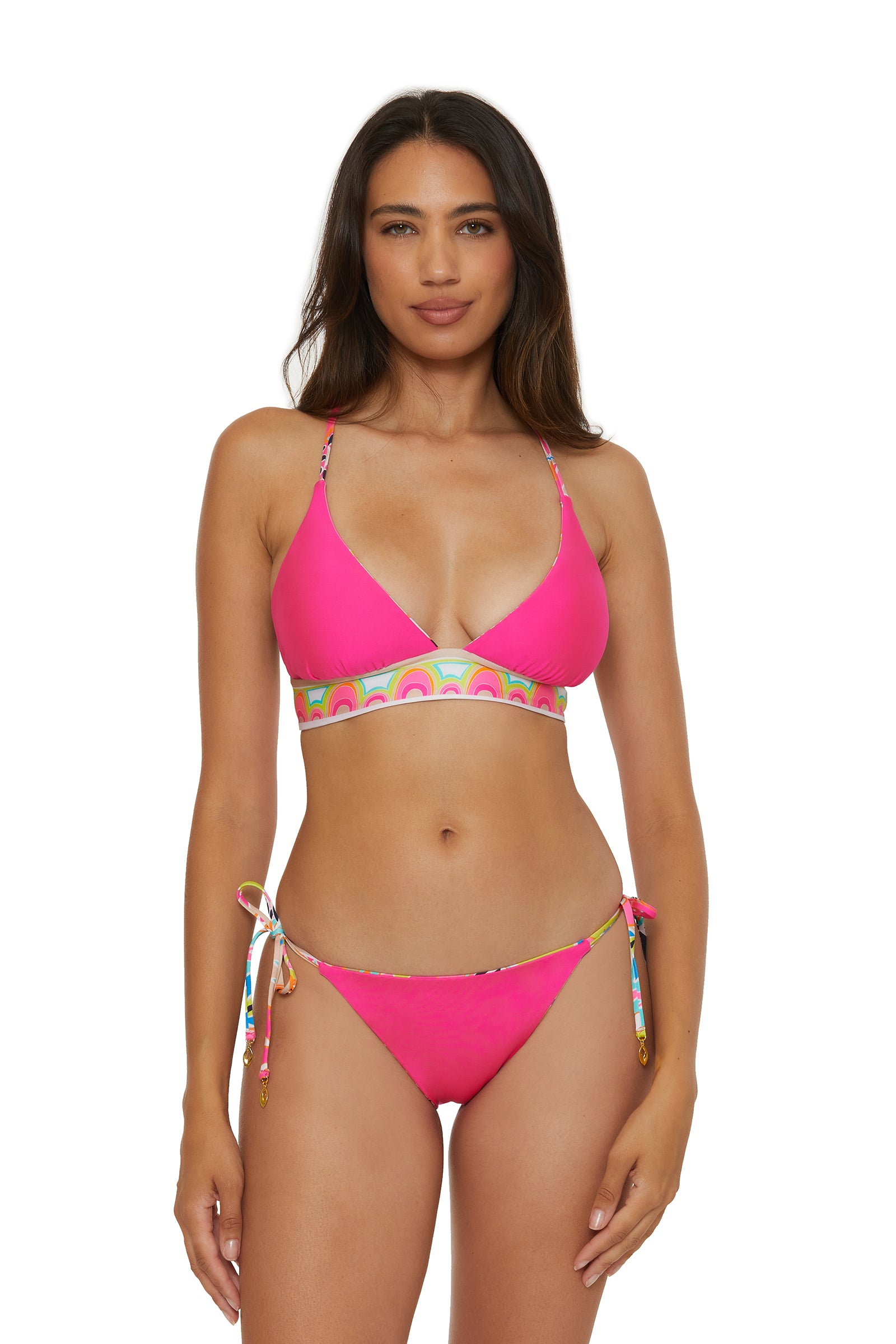 A woman with long brown hair wears the Reversible Halter Bra Swim Top by Venus in bright pink with colorful patterned bands, standing against a plain white background.