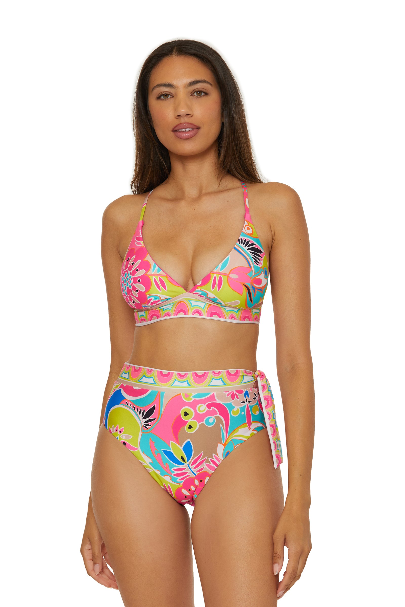 A woman wears the Reversible Halter Bra Swim Top - Venus, a colorful floral bikini with a high-waisted bottom and side tie detail, featuring pink, green, yellow, and blue floral patterns.