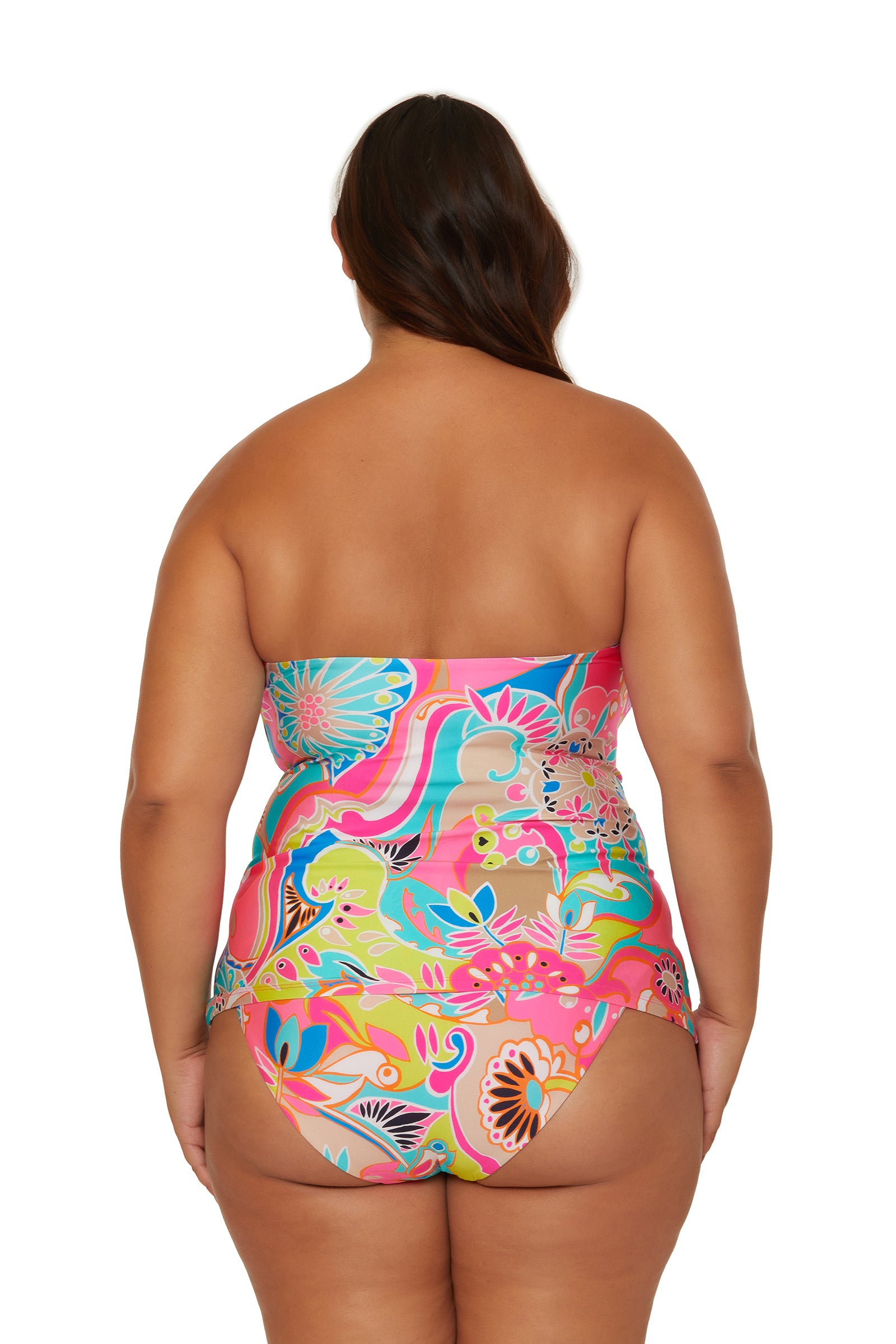 A woman with long brown hair stands with her back to the camera, wearing the colorful, floral-patterned Banded Tankini Swim Top by Venus against a plain white background.