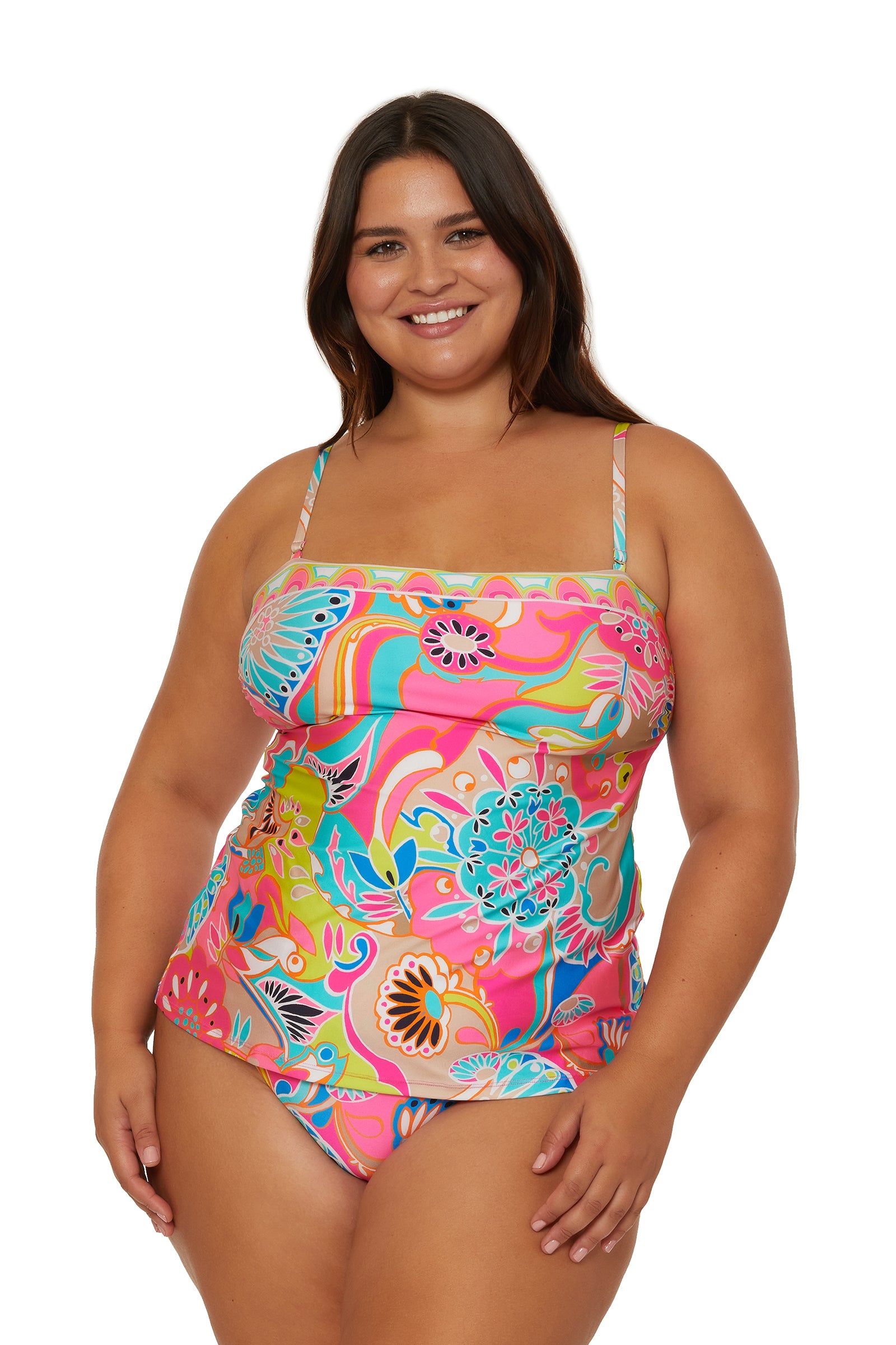 A smiling woman with long brown hair models the Venus Banded Tankini Swim Top, featuring a colorful floral pattern and spaghetti straps, against a white background.