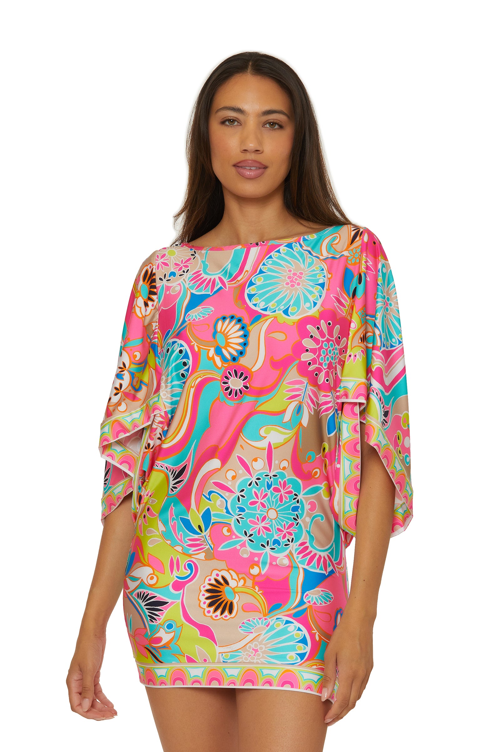 A woman stands facing forward in the Casablanca Tunic Cover-Up in Venus Swim, a short dress with wide sleeves and swirling pink, blue, orange, yellow, and green floral and abstract patterns.