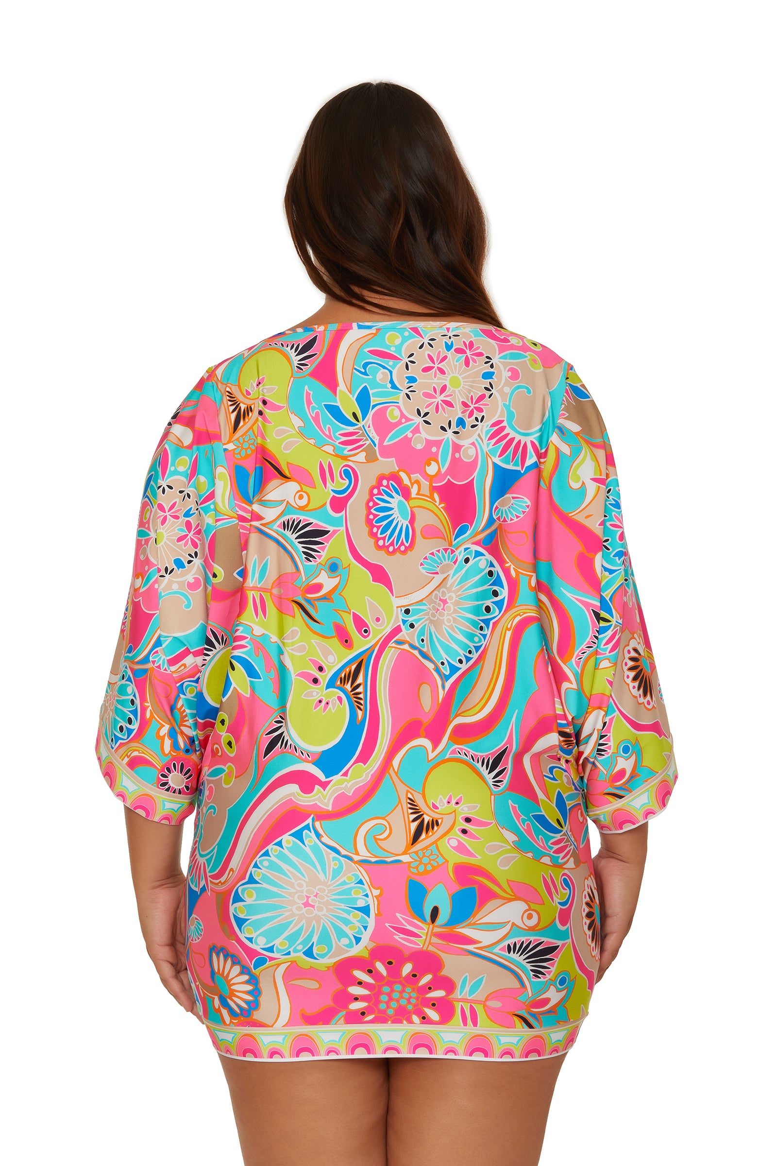 A woman is seen from the back wearing the Casablanca Tunic Cover-Up by Venus, featuring a colorful floral pattern with pink, blue, green, and yellow swirls. The tunic offers three-quarter sleeves and a loose, comfortable fit.