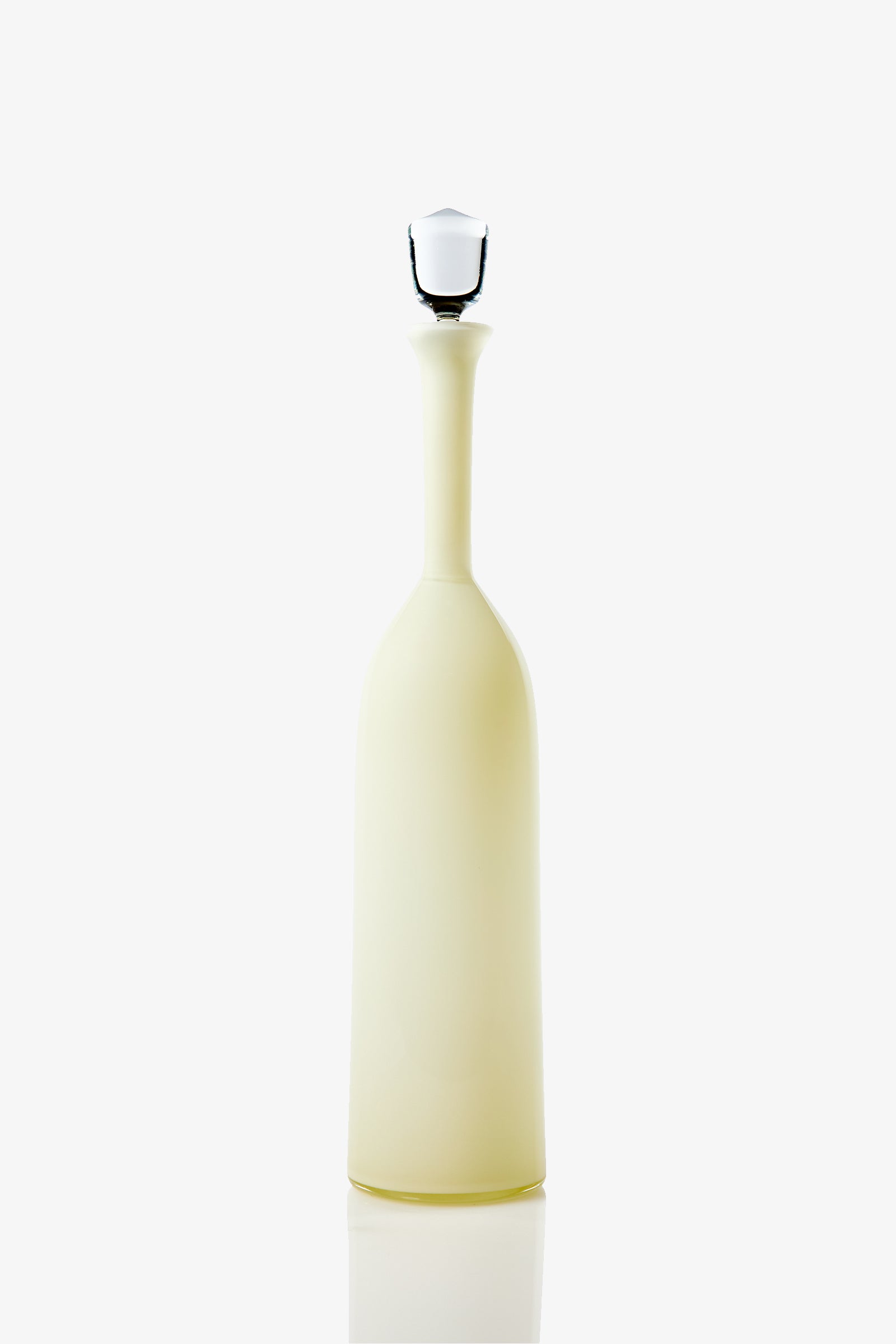 The Wexler Tall Bottle is a tall, slender, opaque pale yellow vessel with a long neck and a white stopper, photographed against a plain white background.