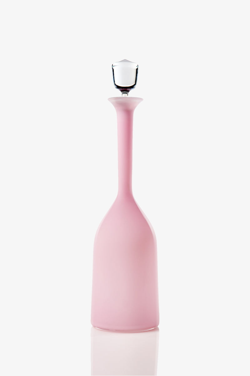 The Wexler Wide Bottle, a tall and slender pink glass vessel with a narrow neck and a clear glass stopper, is displayed against a white background.