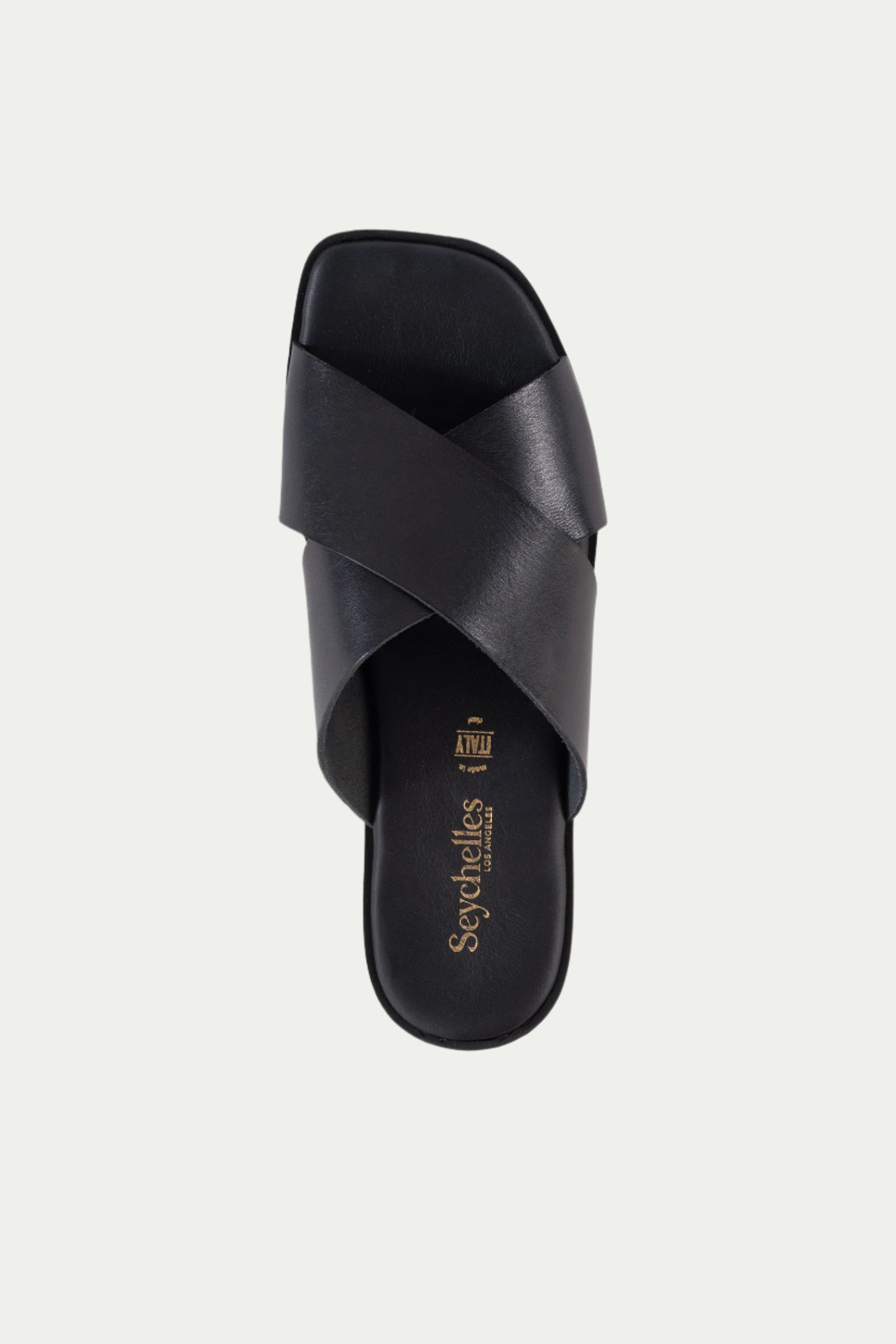 The Chai Sandal - Black Leather features two wide, crisscrossed leather straps, a flat sole, and the Seychelles logo in gold on the insole.