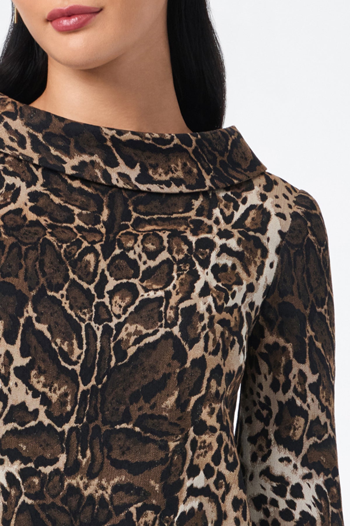 A woman wears the Kailee Top—a long-sleeve, brown and black leopard print top with a wide, folded collar. Only her lower face, neck, and upper torso are shown.