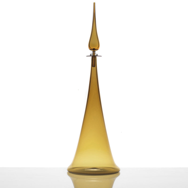 A Large Fluted Cone Decanter featuring a tall, slender amber glass body with a pointed stopper, displayed on a reflective white surface against a plain white background.