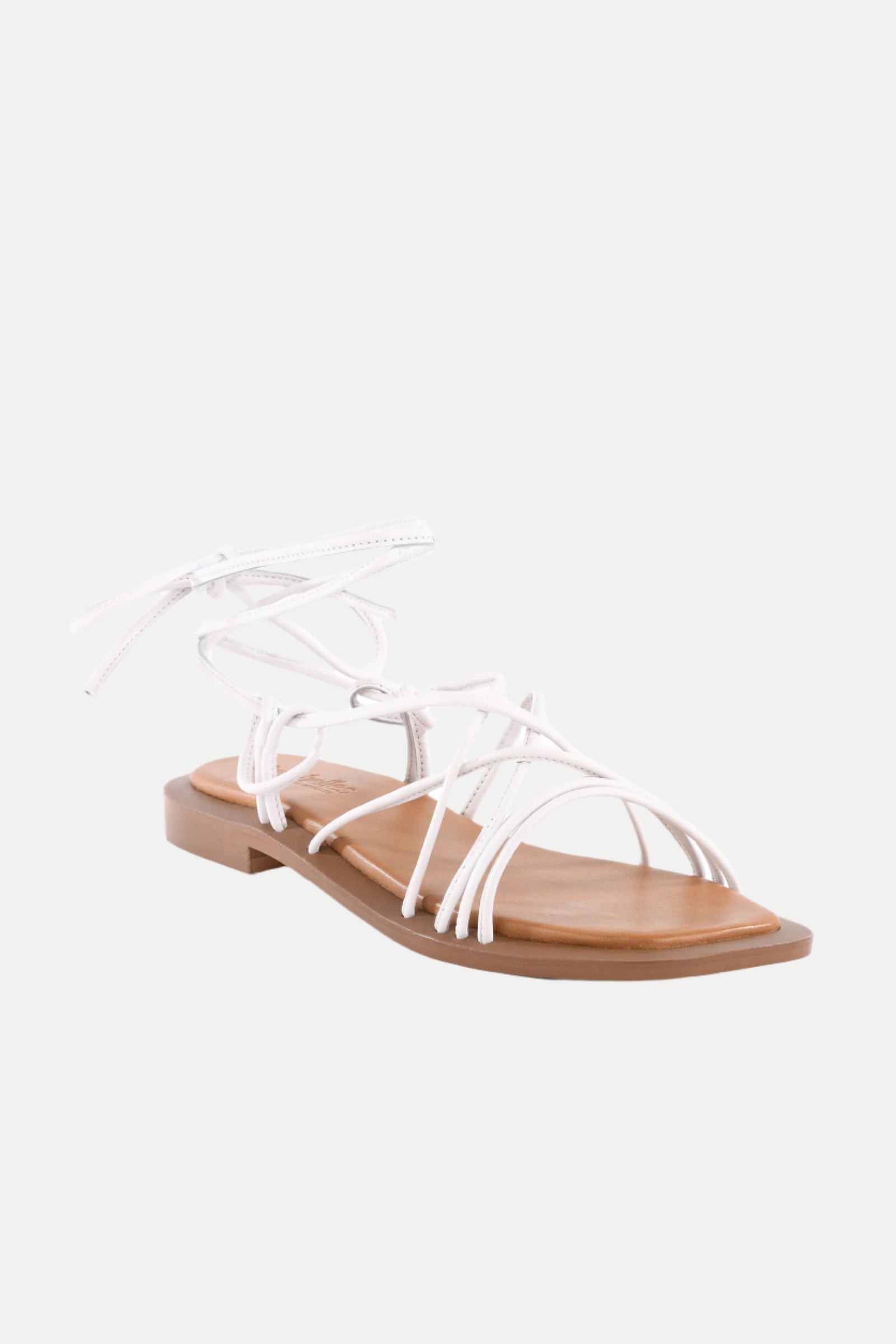 The Lilac Two Flat Leather Gladiator Sandal features white straps, a flat brown sole, open toe, and ankle lace-up closure, shown on a plain white background.