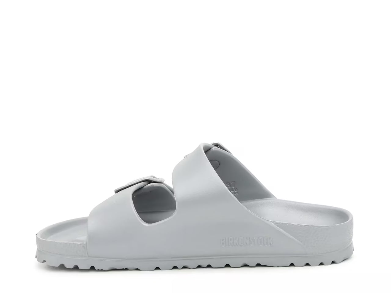 The Birkenstock Arizona Eva Sandal is a light gray slip-on with two adjustable buckle straps, a textured sole, and minimalist design. Birkenstock is embossed on the side. Shown in a side view.