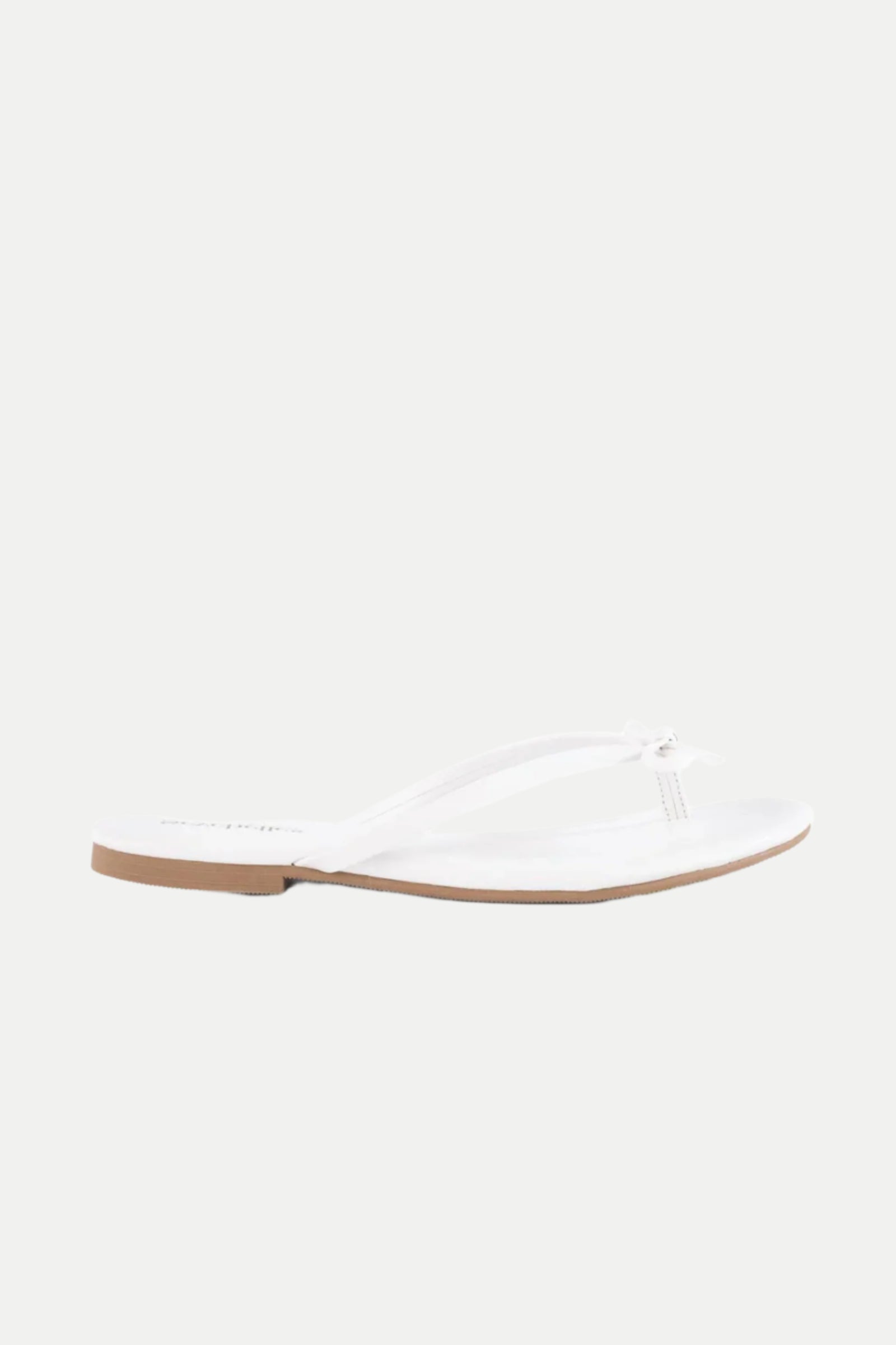 The Wish List Bow Thong Sandal in white features simple thong straps and a thin, flat sole, shown against a plain white background.