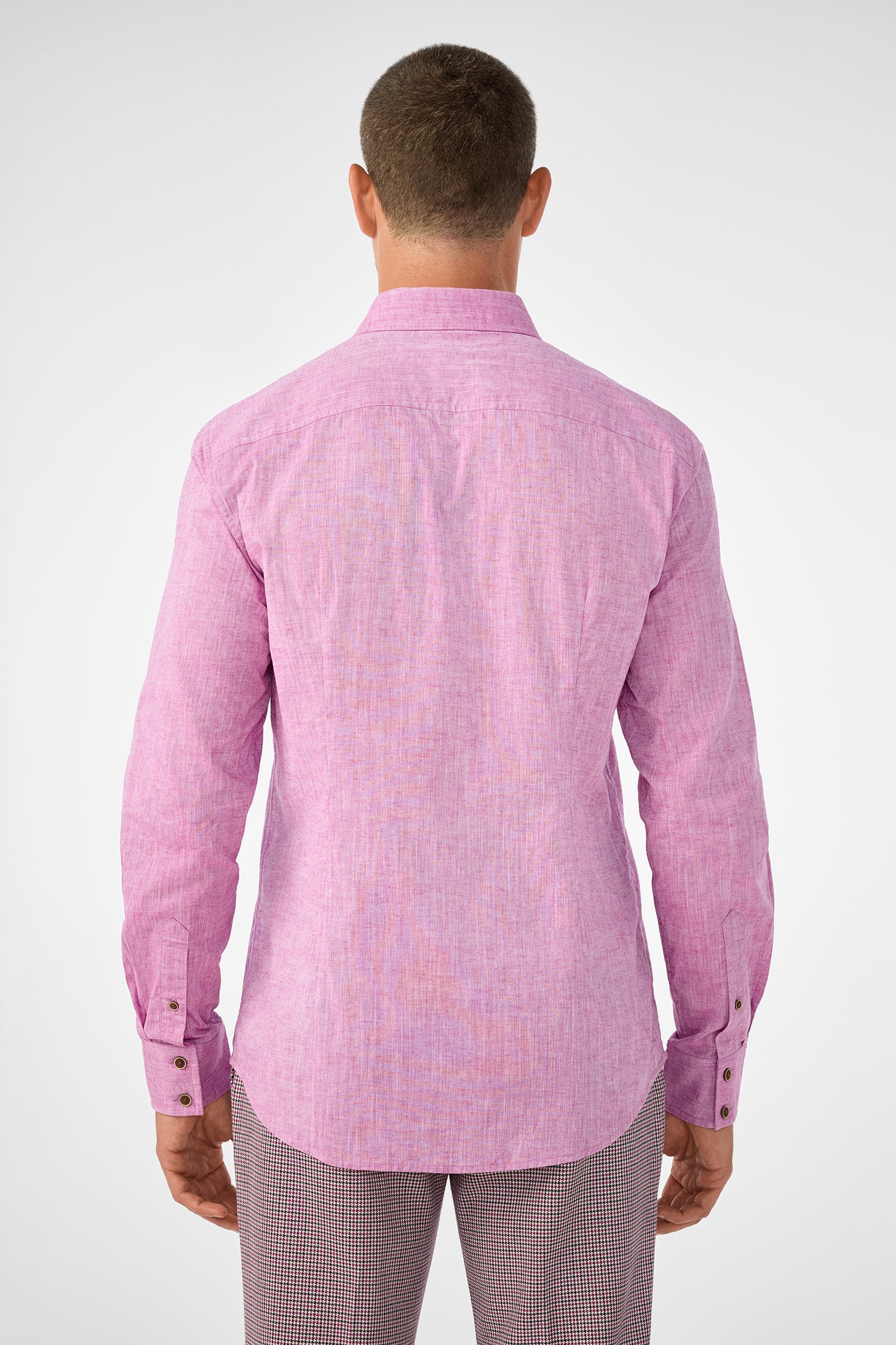 A person stands with their back to the camera, wearing the Aaron Slim Fit Long-Sleeve Shirt in Geranium and patterned pants against a plain, neutral background.