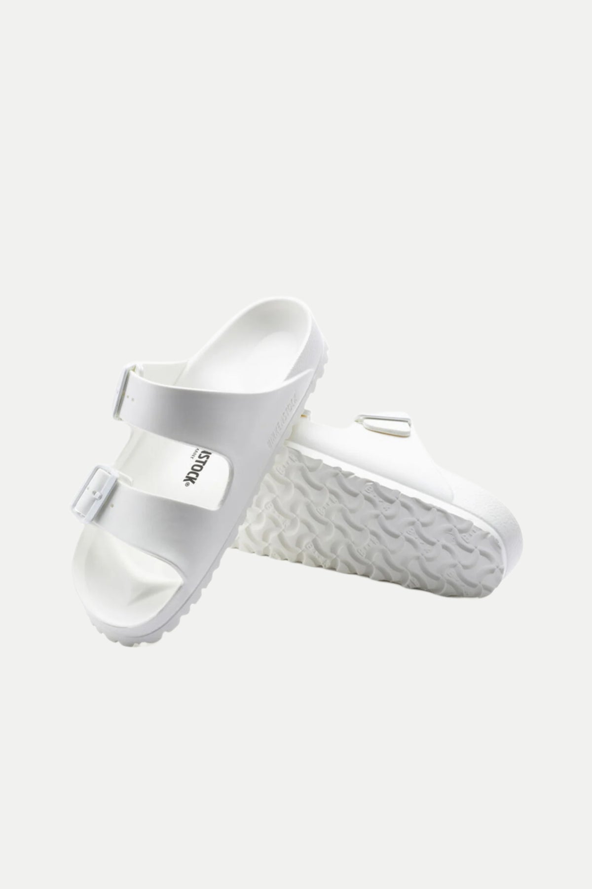 The Mens Arizona White Eva Slide Sandal features two buckle straps. Displayed on a white background, one sandal stands upright to reveal the textured sole, while the other lies flat.