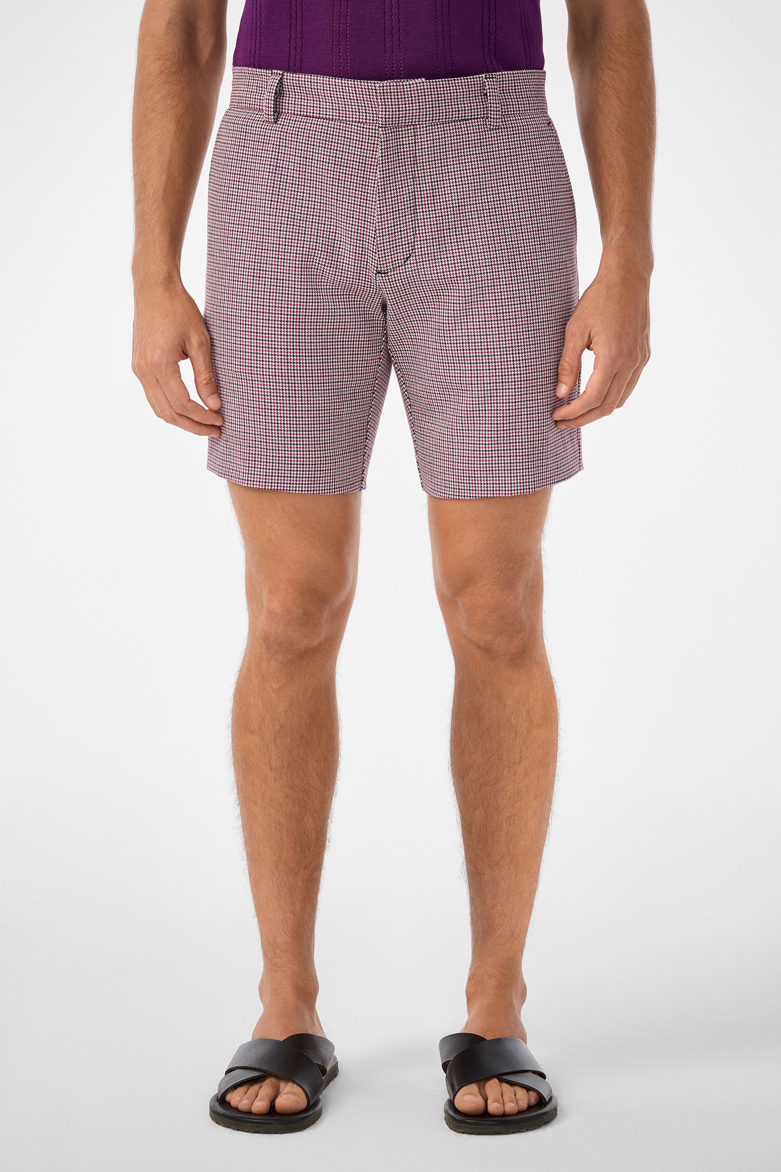 A person stands facing forward wearing a purple textured shirt, Lawrence Short in red and white pattern, and black sandals. The image shows them from mid-torso to feet against a plain white background.
