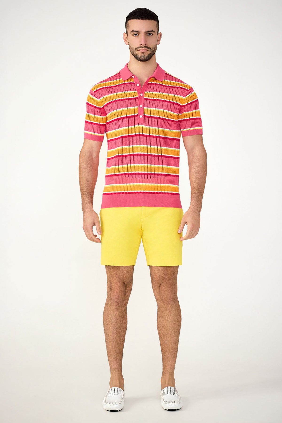 A man faces forward wearing the Viviano Short-Sleeve Mesh Polo with colorful stripes in red, pink, and yellow, paired with yellow shorts and white slip-on shoes against a plain light background.