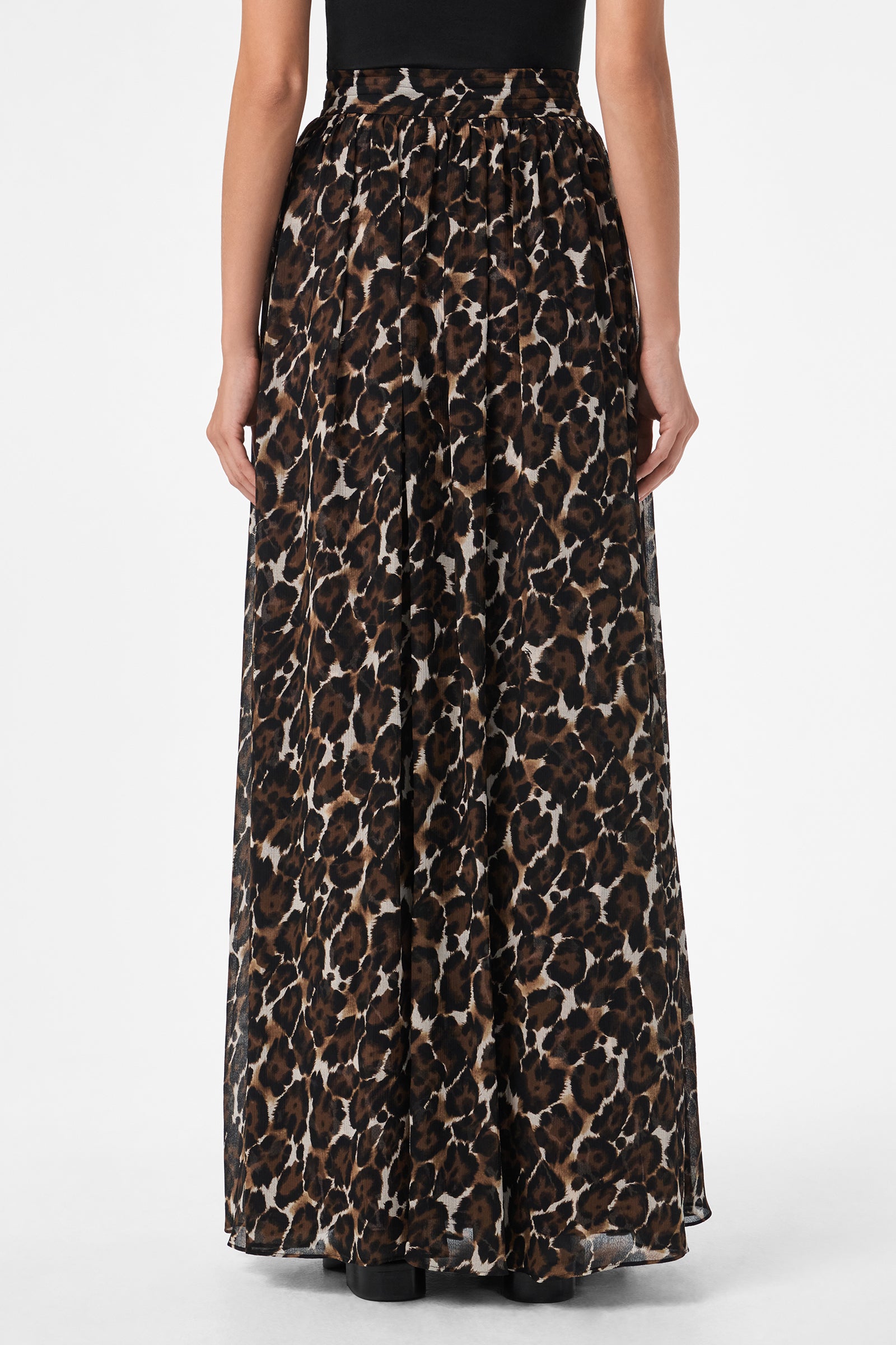 A person shown from the back wears the Bersha Skirt, a long, flowing skirt featuring a black, brown, and beige leopard print pattern, paired with a black top.