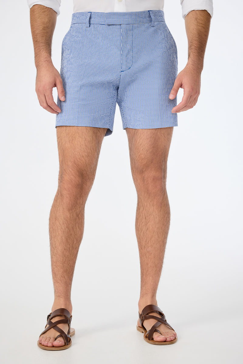 A man stands against a white background, wearing the Roger Short in Ocean Gingham. The image is cropped just below his shoulders to highlight the shorts and legs.