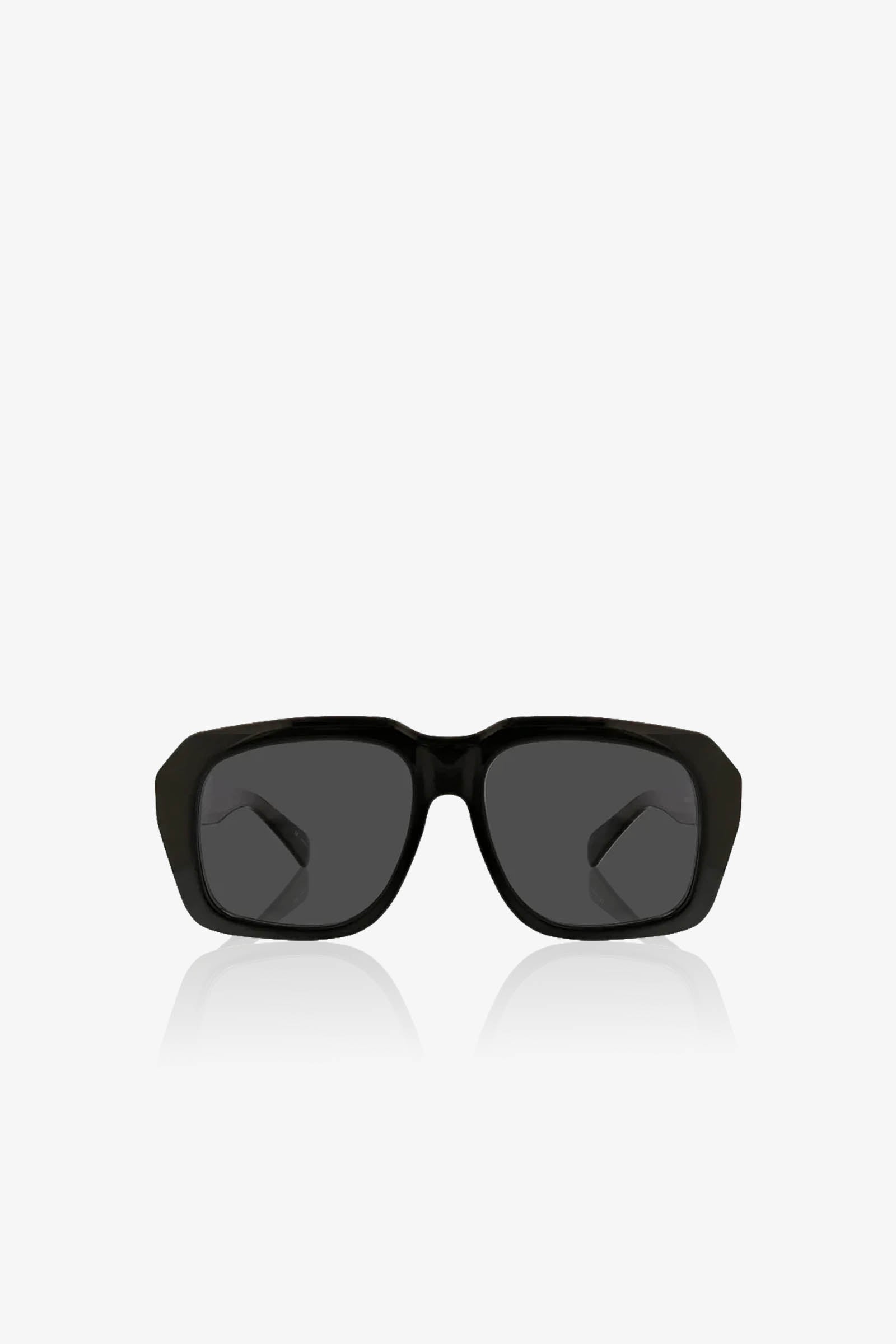 The Andros Sunglass, featuring a black rectangular frame with dark lenses, is centered on a plain white background and shown from the front, with its arms slightly visible behind the lenses.
