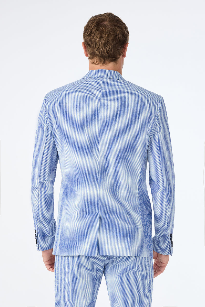 A man is seen from behind wearing the Louie Blazer in Ocean Gingham, featuring a light blue and white checkered pattern, paired with matching trousers against a plain light background.