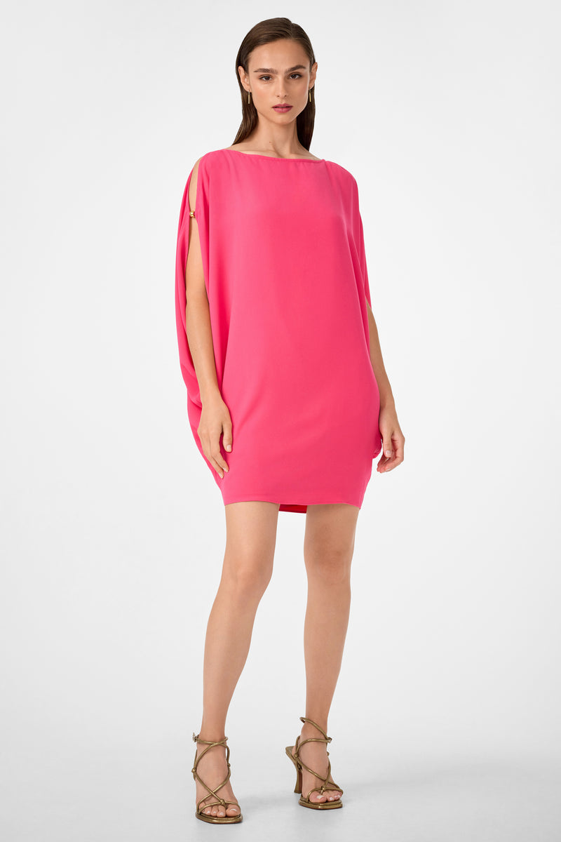 A woman with straight brown hair and a confident expression stands against a white background wearing the Razu Short Split Sleeve Mini Dress in Rosewater and strappy high-heeled sandals.