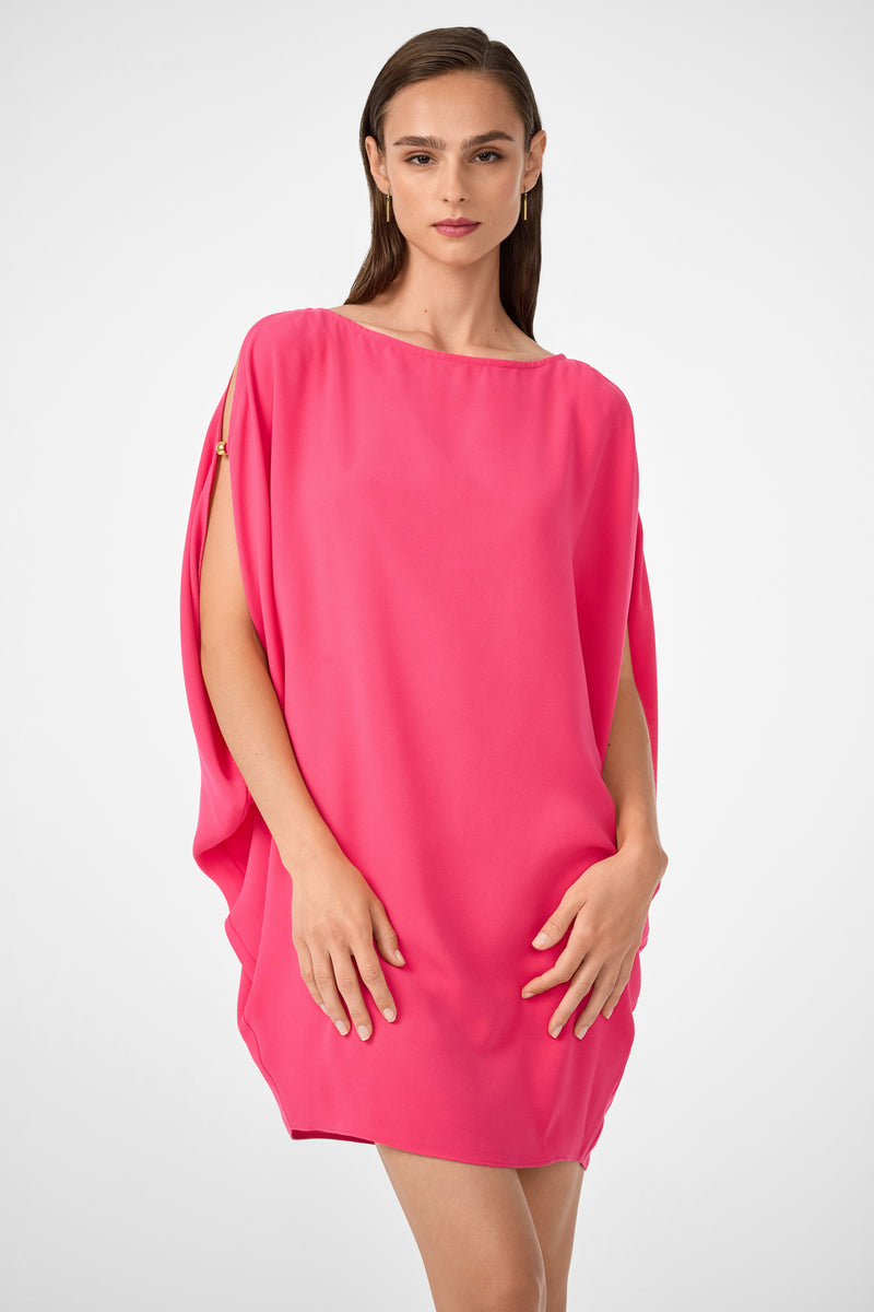 A woman with straight brown hair wears the Razu Short Split Sleeve Mini Dress in bright pink, featuring loose fit and cape-like sleeves, standing against a plain white background.