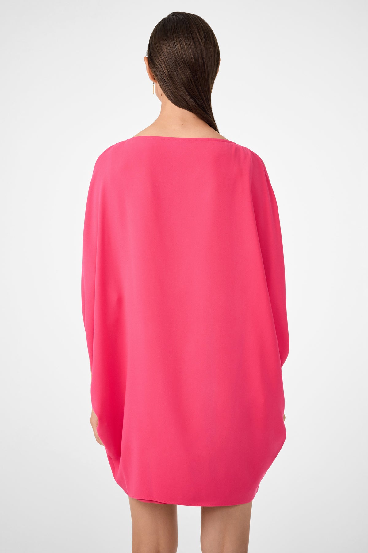 A person with long, straight brown hair, seen from behind, wears the Razu Short Split Sleeve Mini Dress in bright pink with long sleeves, standing against a plain white background.