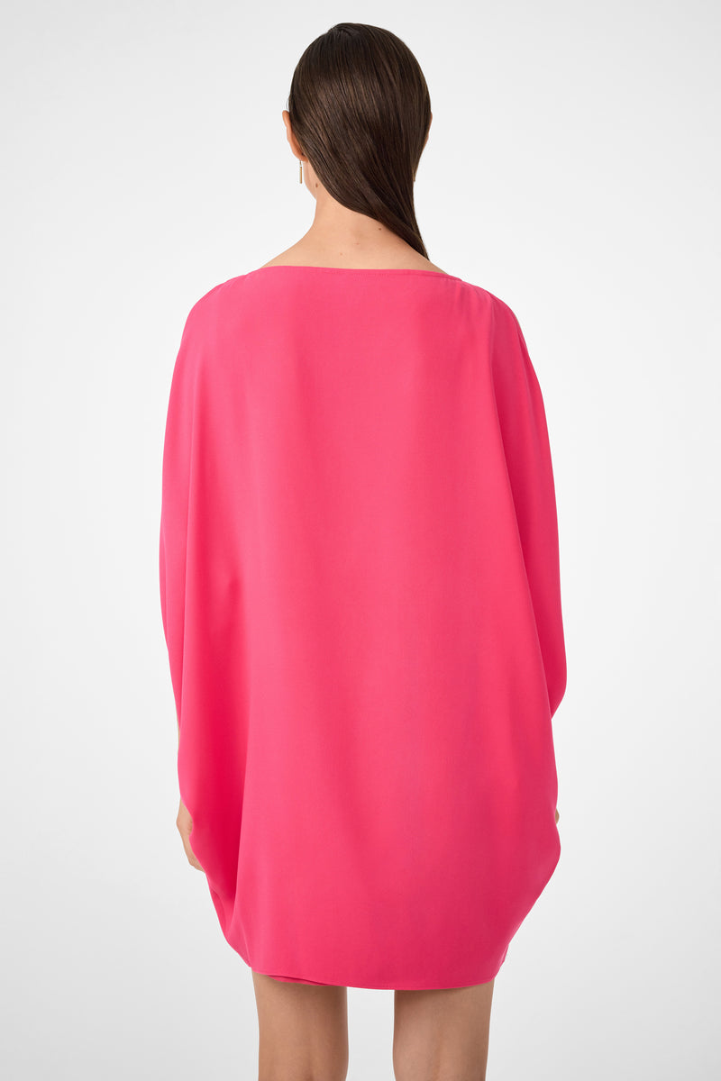 A person with long, straight brown hair, seen from behind, wears the Razu Short Split Sleeve Mini Dress in bright pink with long sleeves, standing against a plain white background.