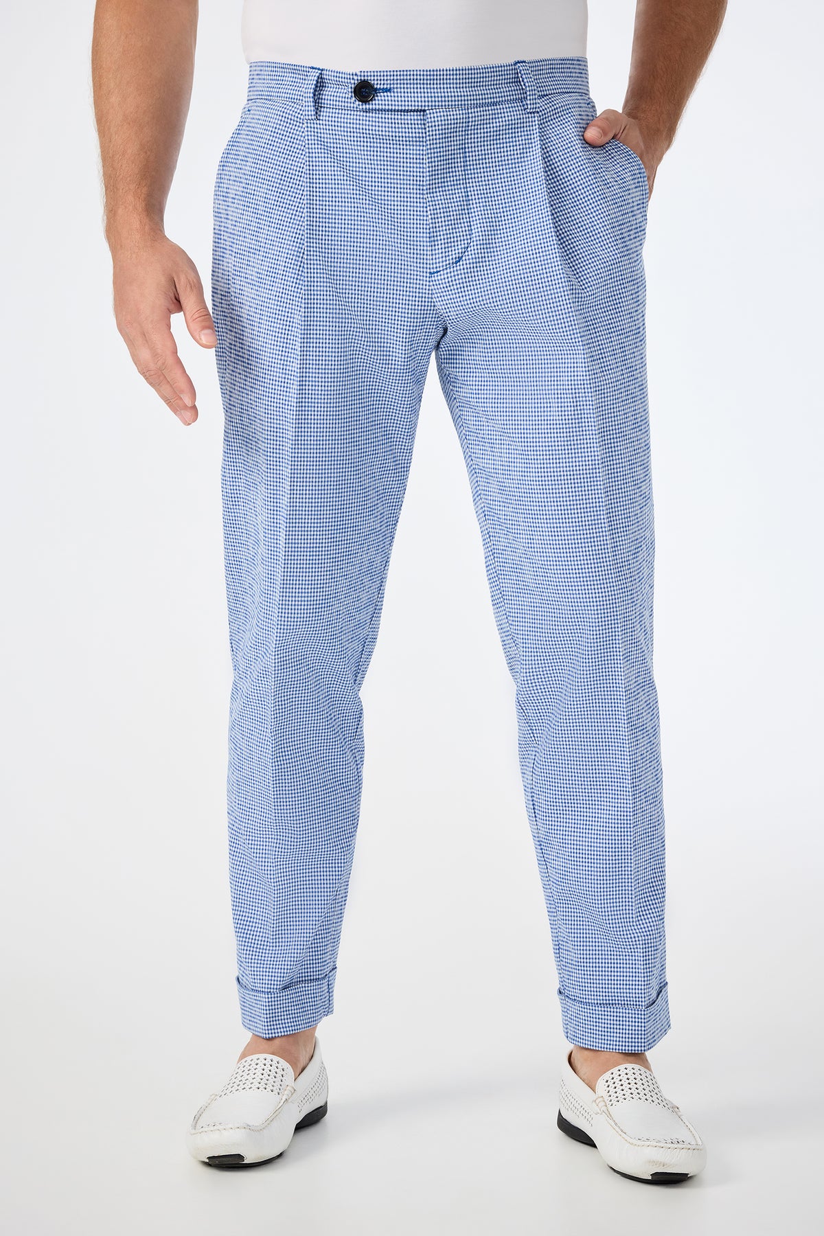 Someone wears the Beale Pleated Trouser in Ocean Gingham, styled with a white shirt and loafers, hands by their sides, shown from mid-torso down against a plain white background.